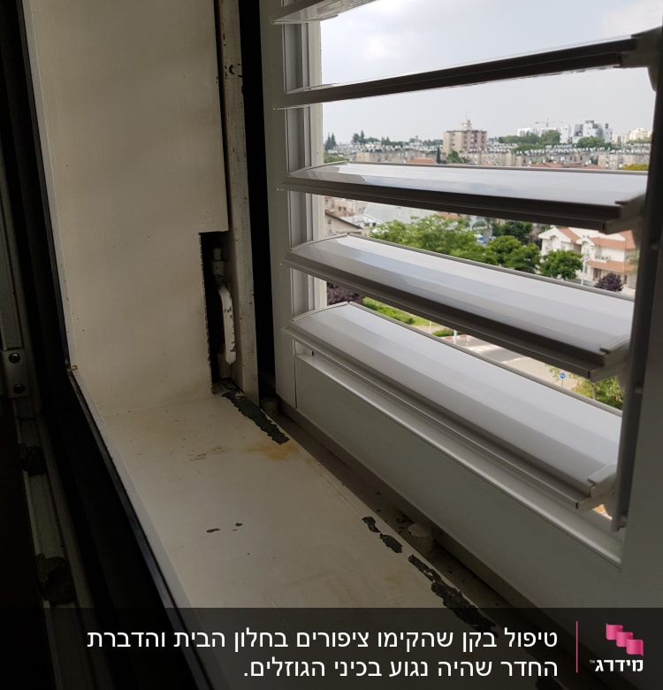 חלון פתוח עם סימני חלודה על אדן החלון